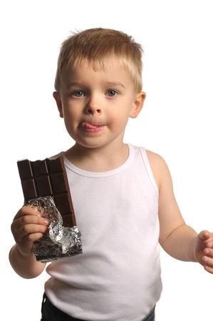 Picture of a little blond boy with his tongue out holding chocolate の写真素材