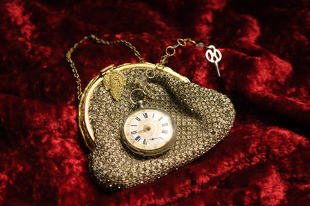 Small woman's handbag with pocketwatch on a red background