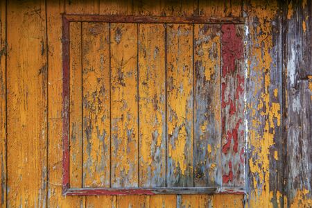 yellow , red and orange paint on old wooden house wallの写真素材