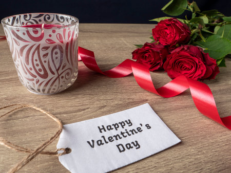 Red roses with white note ribbon and red candle on the tableの写真素材