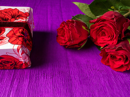 Red roses with red gift on purple backgroundの写真素材