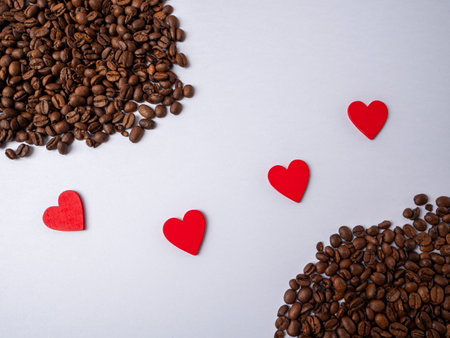 Four hearts lie between two heaps of coffee beans which are apart on a white bright backgroundの写真素材