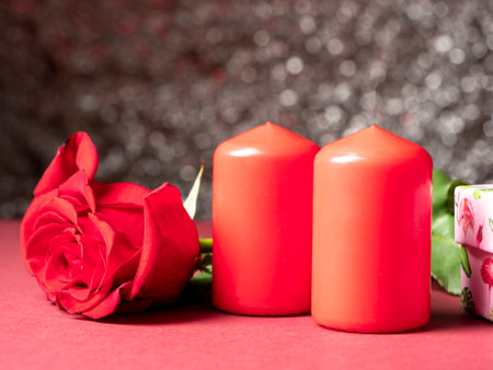 Red big rose which is next to two red candles which are on a white backgroundの写真素材
