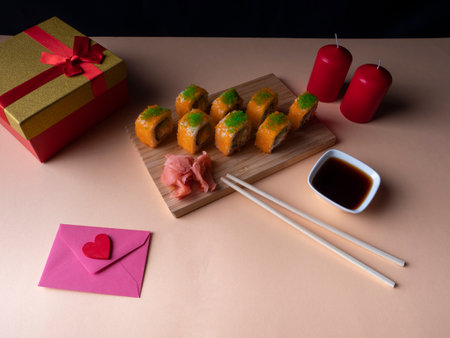 A lot of yellow sushi on the board and next to it there are two red candles and two blue masks, and a yellow-red gift with a red ribbon on a yellow backgroundの写真素材