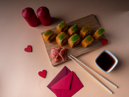 A lot of yellow sushi on a board and two red candles and two red envelopes are standing next to it on a yellow backgroundの写真素材