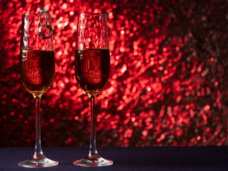 Two glasses of champagne stand on a blue surface with each other on a pink backgroundの写真素材
