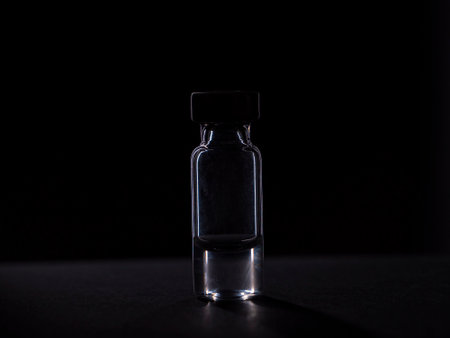 A glass bottle containing a liquid with a vaccine. Isolated on black backgroundの写真素材