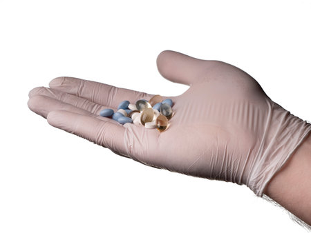 A doctor in medical gloves holds various pills in his hand. Pills and hand isolated on white backgroundの写真素材