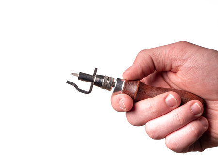 Stitching Groover for marking edges, is in the man's hand. Leather tool and hand isolated on white backgroundの写真素材