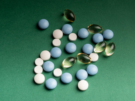 Omega 3 capsules and different medical pills lie isolated on a green background. Close-up...
