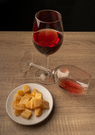 Two glasses of wine, one of them lying side by side, and in front of them is a white plate of sliced ââcheese.の写真素材