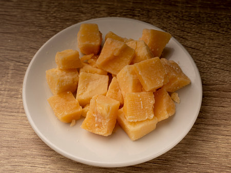 Close-up of sliced cheese that lies on a white plate, and the plate lies on a wooden tableの写真素材