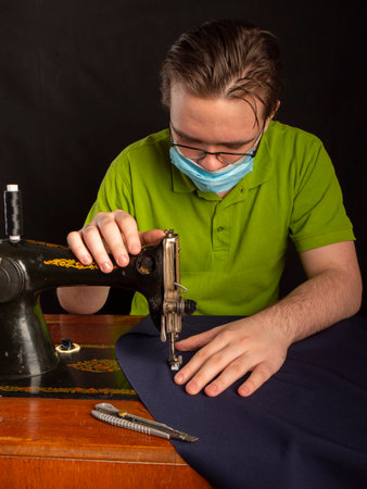 A master sews something from a blue fabric on a sewing machine Sewing workshop conceptの写真素材