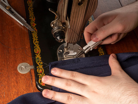 A master sews something from a blue fabric on a sewing machine Sewing workshop conceptの写真素材
