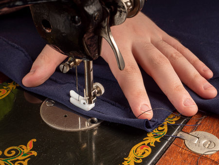 A master sews something from a blue fabric on a sewing machine Sewing workshop conceptの写真素材