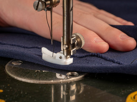 A master sews something from a blue fabric on a sewing machine Sewing workshop conceptの写真素材