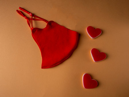 Red mask which is located next to three white and red hearts with an inscription on an orange background.の写真素材