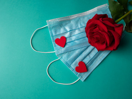 Two blue masks on which there are two red hearts and a red rose that is on masks, on a green backgroundの写真素材