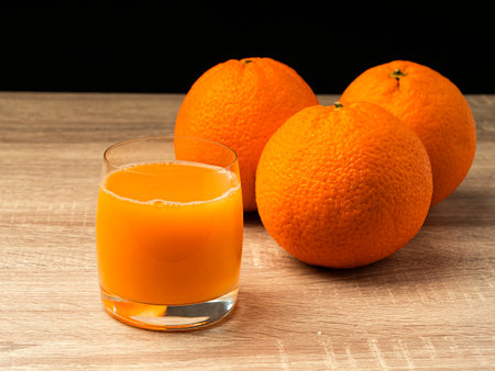Glass glass with orange juice and orange stand on a wooden gray table on a dark background Fresh juice conceptの写真素材
