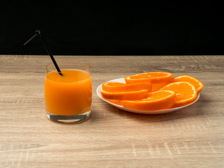 Glass glass with orange juice and orange stand on a wooden gray table on a dark background Fresh juice conceptの写真素材