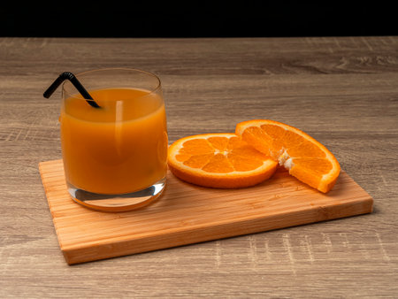 Glass glass with orange juice and orange stand on a wooden gray table on a dark background Fresh juice conceptの写真素材
