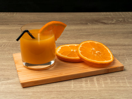 Glass glass with orange juice and orange stand on a wooden gray table on a dark background Fresh juice conceptの写真素材