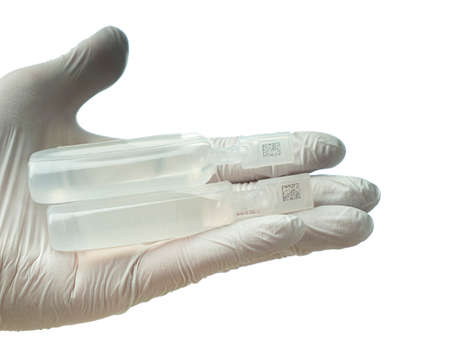 In the outstretched hand of the young doctor lie vials of vaccine liquid.の写真素材