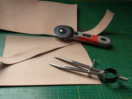 Making a leather case for batteries by a tanner, on a green self-healing mat, leather craftsmanship conceptの写真素材