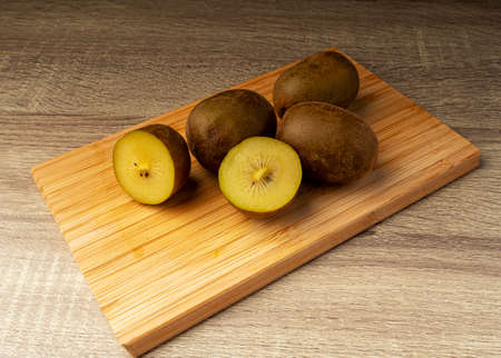 golden kiwi whole and slices on wooden table, healthy food and fruit conceptの写真素材