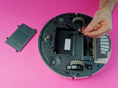 The robot vacuum cleaner is disassembled, the vacuum cleaner is being cleaned and disassembled, the concept of repairing a robot vacuum cleaner, and advertising prevention and replacement of filtersの写真素材