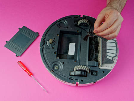 The robot vacuum cleaner is disassembled, the vacuum cleaner is being cleaned and disassembled, the concept of repairing a robot vacuum cleaner, and advertising prevention and replacement of filtersの写真素材