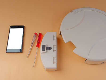 The robot vacuum cleaner is disassembled, the vacuum cleaner is being cleaned and disassembled, the concept of repairing a robot vacuum cleaner, and advertising prevention and replacement of filtersの写真素材
