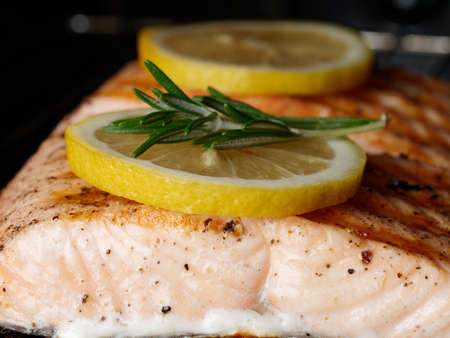 Close-up of ready-made salmon fillet with two lemons and rosemary, salmon in the oven. Healthy food conceptの写真素材