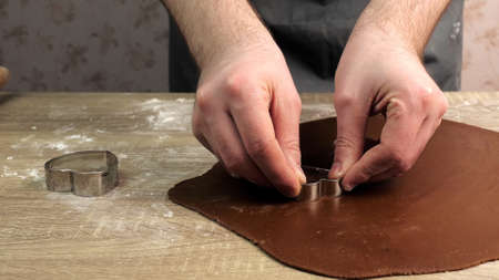 A young chef carves the shape of a heart on a gingerbread dough using iron shapes. Baking conceptの写真素材