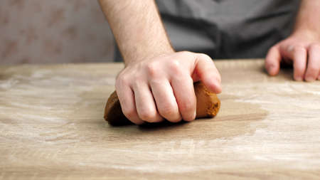 A young cook is kneading the gingerbread dough, on a wooden table on which there is flour. Baking conceptの写真素材