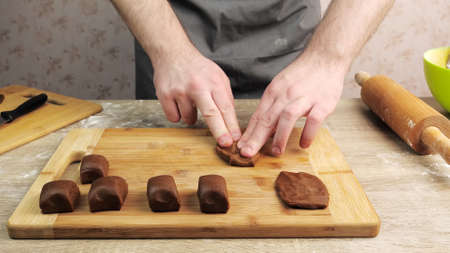 A young chef takes pieces of ginger dough and kneads them into flat circles. Baking conceptの写真素材