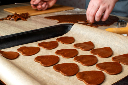 A young chef separates from each other the cut forms in the ginger dough, which lies on a wooden tableの写真素材