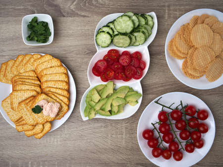 Serving salted crackers, cheese paste with crab meat, avocado, tomatoes and cucumber, healthy diet food concept.の写真素材
