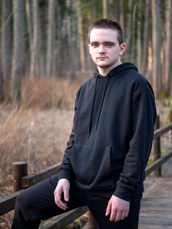 A guy in a black tracksuit, a portrait on a forest background, the sun at sunset, the guy goes in for sports, the concept of a healthy lifestyle.の写真素材