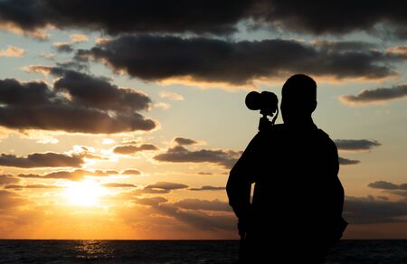 Silhouette the photographer shooting a colorful sea sunset.の写真素材