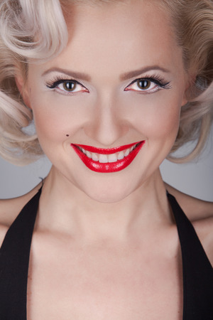 Pretty blond girl model like Marilyn Monroe in black dress with red lips on gray backgroundの写真素材