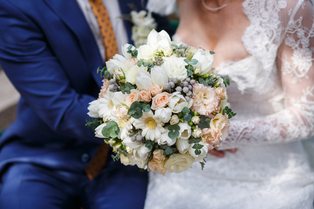 Bride and groom holding in hand beautiful wedding bouquetの写真素材