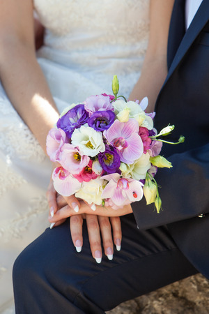 hands of bride and groom with bouquetの写真素材