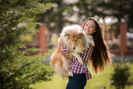 young beautiful woman with long hair walking with collie dog. Outdoors in the park.の写真素材