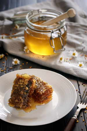 Fresh Honeycombs on plate, honey and pollen on backgroundの写真素材