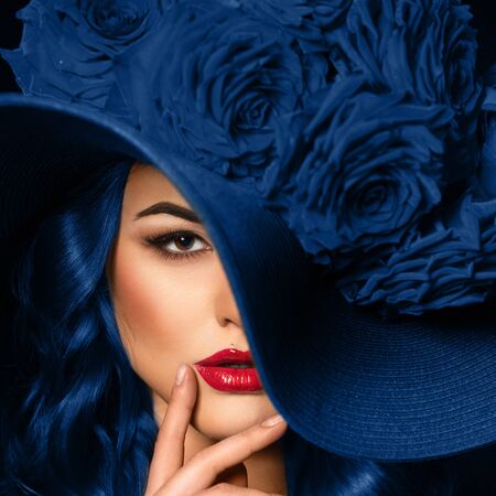 Portrait of a beautiful woman with blue lips in a hat, toned in color of the year 2020, classic blue.の写真素材