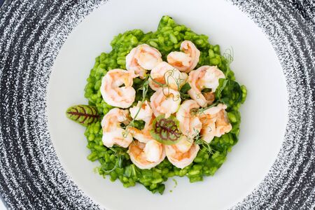Risotto with basil and shrimp decorated with microgreens in a plate.の写真素材