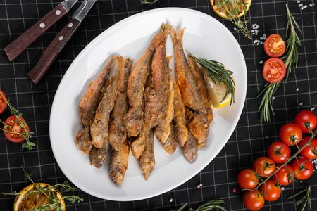 A dish of fried red mullet. Table setting, decorated with greens and cherry tomatoes.の写真素材