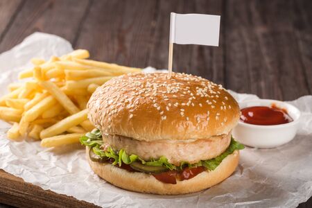 Chicken burger on a wooden board. Served with french fries and tomato ketchup.の写真素材