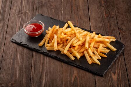 Fried fries on a stone black board, served with tomato ketchup.の写真素材